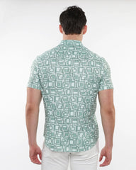 A man wearing a light green squares print open knit shirt with an intricate white and dark green geometric pattern