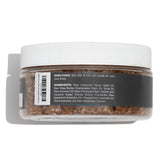 A clear plastic jar with a white lid contains brown granular stay ready scrub body scrub with label directions