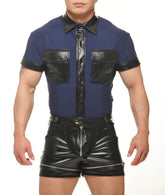 A man wears a navy blue muscle top with black faux-leather trim, collar, and chest pockets, paired with black shorts.