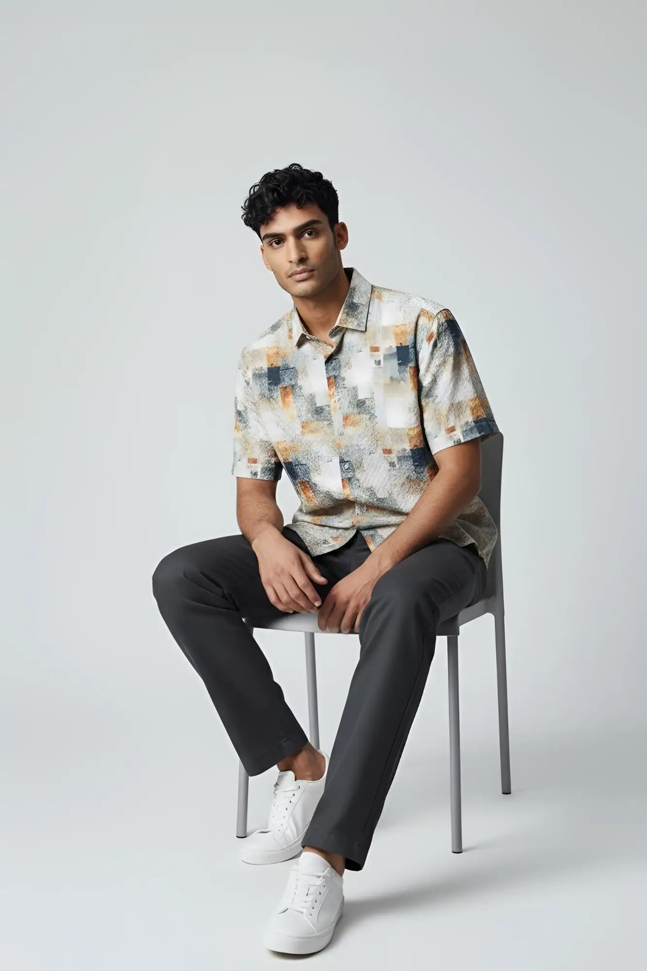 A man wearing a suslo crinkled fabric s s shirt with abstract geometric pattern in beige gray and orange tones