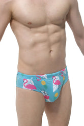 Bright turquoise swim brief pina colada with male cup pad featuring pink flamingos yellow pineapples and white leaves