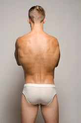 A man wearing the back side of white striped tartarus buckle brief underwear with a secure buckle feature