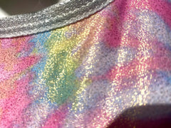 A tie dye crop top with a shimmering iridescent rainbow gradient and silver glitter trim