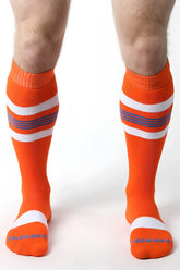Bright orange tight end knee high socks with white and purple stripes and ribbed cuff and toe design