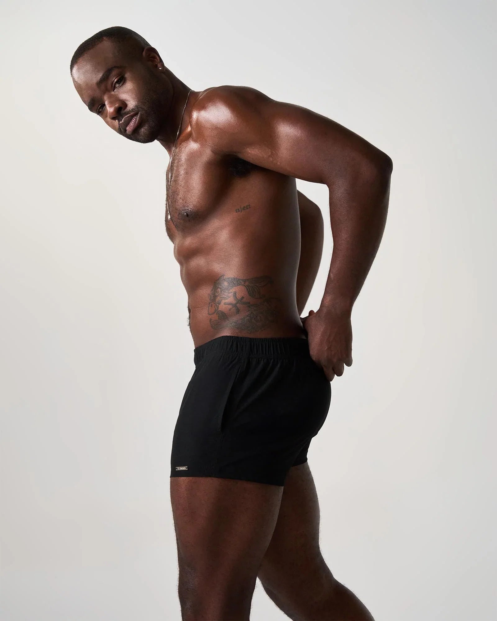 Black athletic swim shorts with a small white logo on the lower left leg designed for statement swimwear use