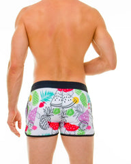 White swim trunks with a vibrant tropical fruit pattern of pineapples watermelons and limes in bright colors