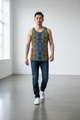 A man wears a Tulio Swimwear Rainbow Maze tank top, blue jeans, and white sneakers, standing in a bright studio.
