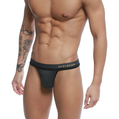 Black ustation talent thong with subtle heathered texture and gold lettering on the waistband front side