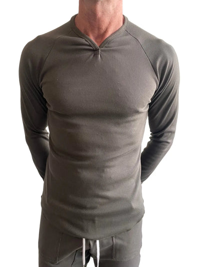 Man in olive ribbed long-sleeve shirt with raglan sleeves, white background.