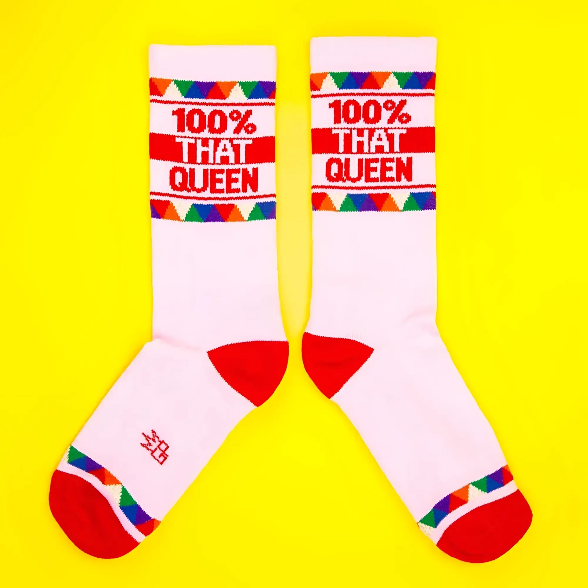 White crew socks with red toe and heel featuring 100% that queen text and colorful triangular cuff pattern