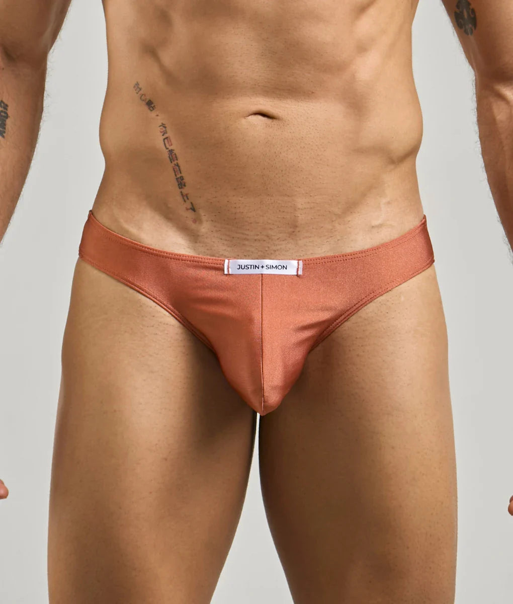 Coral-colored satin briefs with a white justin + simon label at the waistband from the classic mens bikini collection