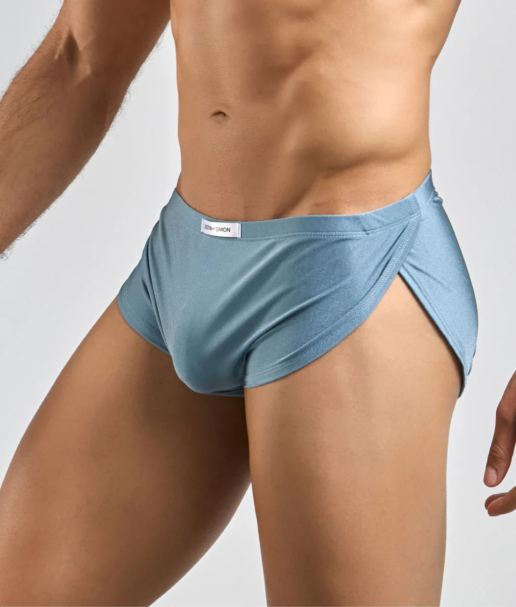 Light blue smooth textured men’s briefs with elastic waistband and subtle side slit from Justin Simon Running Short collection