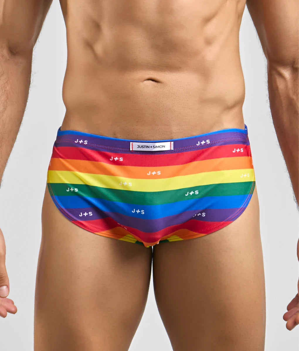 Justin simon running short rainbow-striped men’s swim trunks with vibrant colors and repeating j+s branding