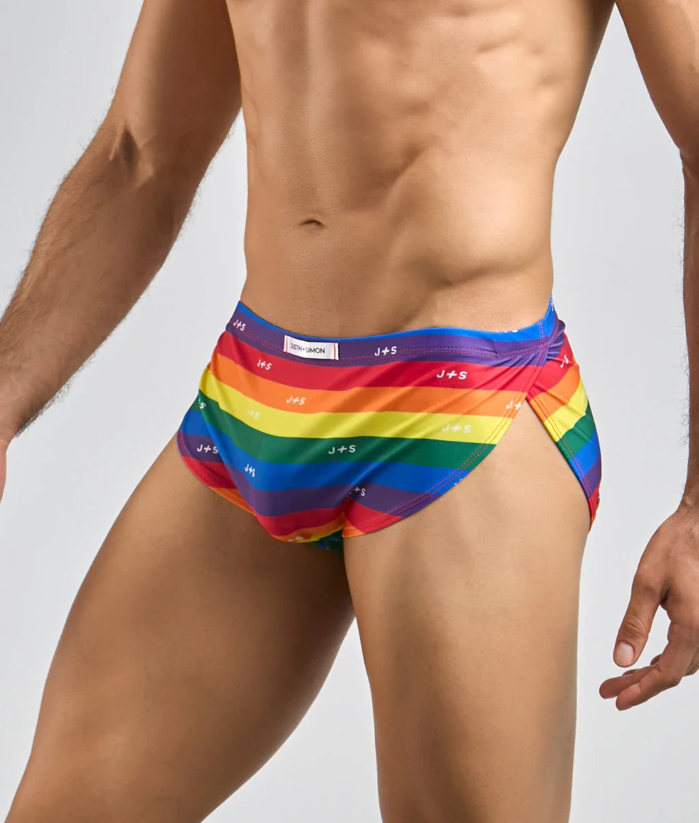 Justin simon running short rainbow-striped men’s swim trunks with vibrant multicolored design and repeating logo