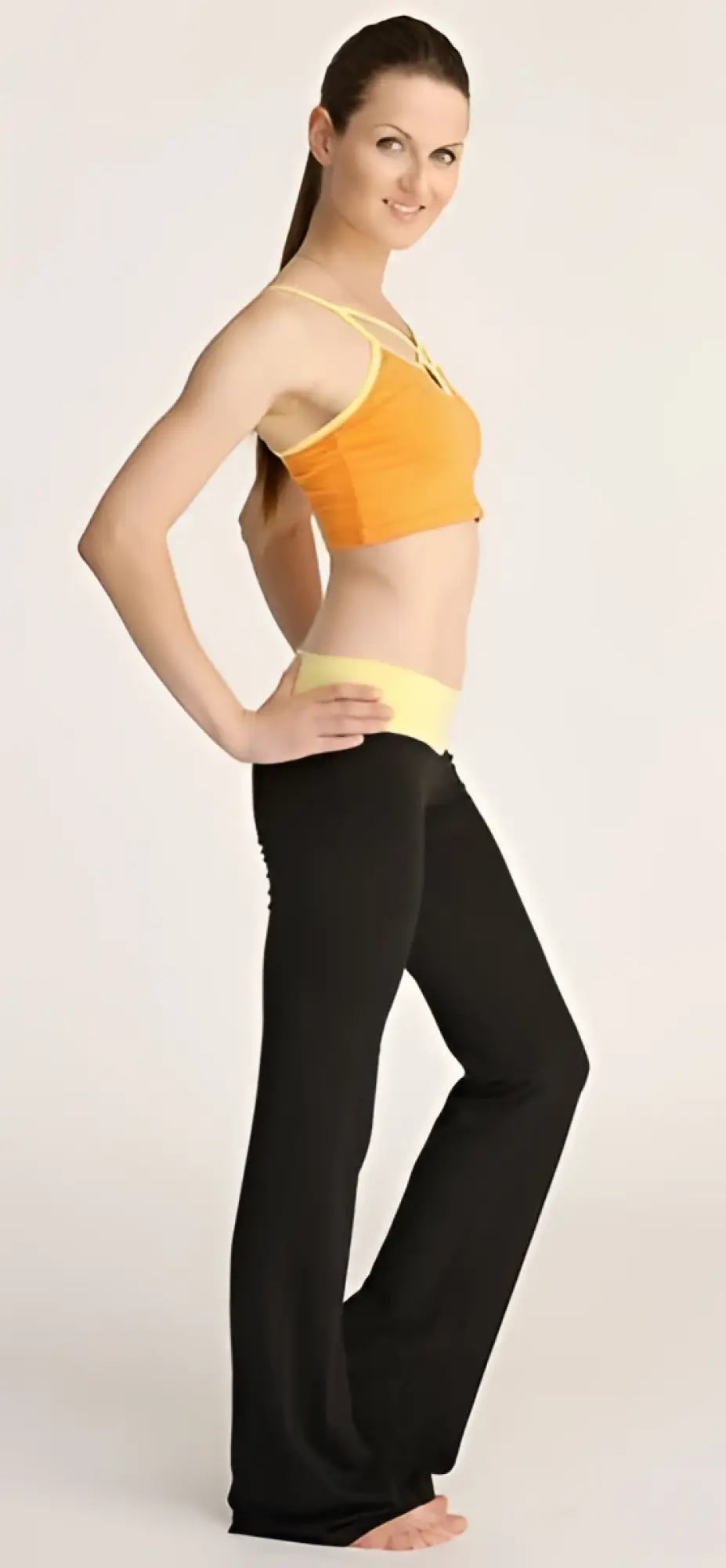 A woman wearing a vibrant orange sports bra with yellow trim and black flared 4-rth women’s classic yoga pants