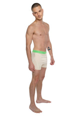 Cream-colored boxer briefs with bright green elastic waistband and brand logo shown with performance yoga leggings sand beige