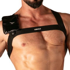 Close-up of a man's chest wearing a black adjustable harness with a small pouch on the shoulder and Absolu Male By TOF Paris logo