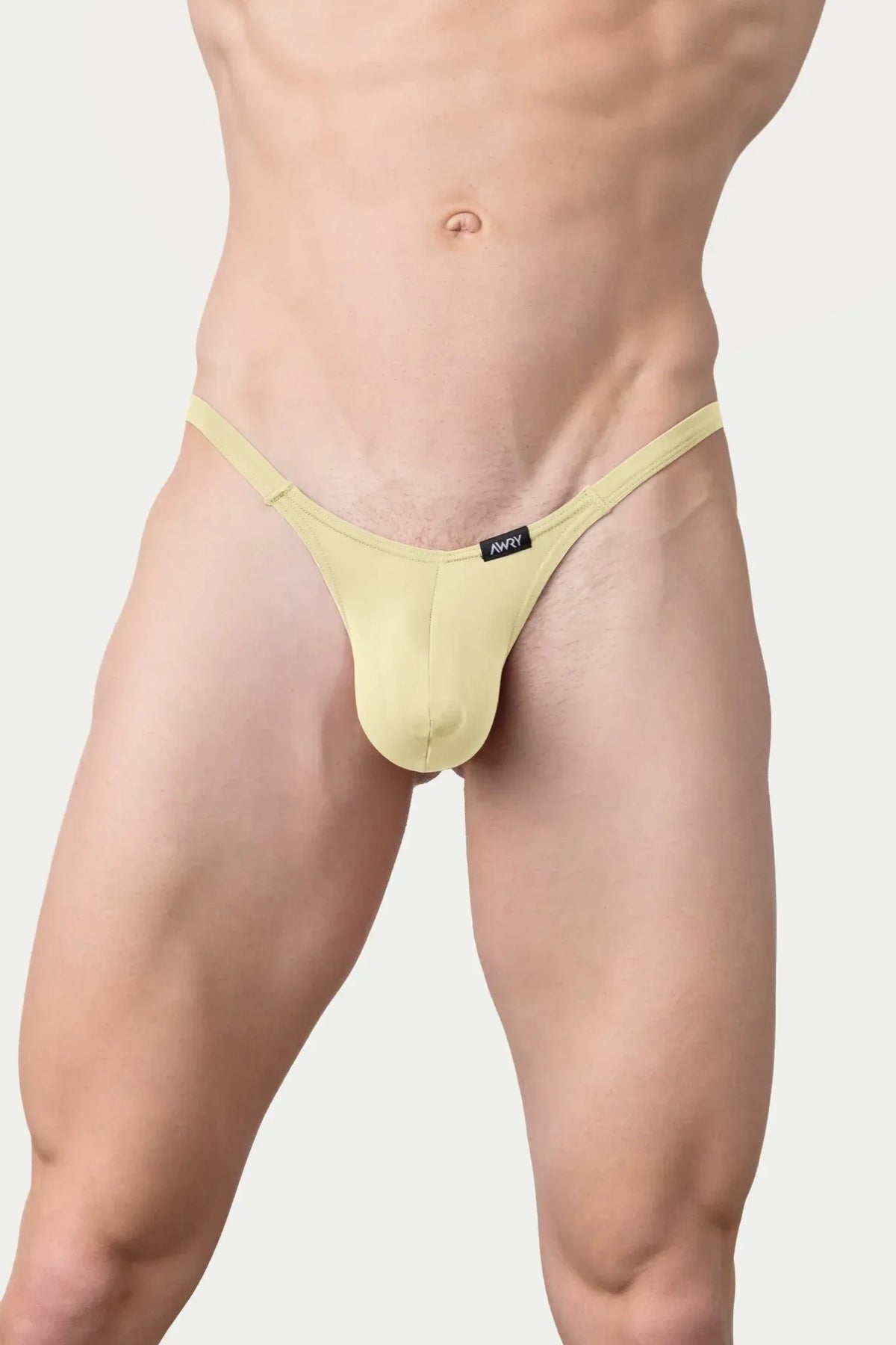 A man wearing light yellow AWRY Menswear Pulse V-String underwear against a plain light gray background.