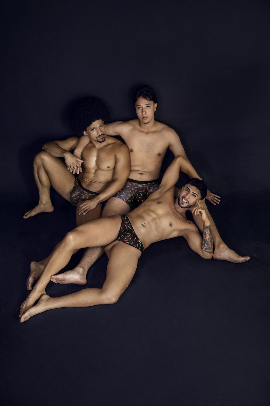 Three men posing in matching CandyMan 99873 chili pepper black print trunks with dark patterned fabric