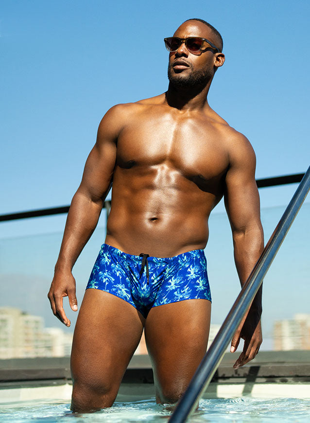 Blue swim trunks with a white palm tree pattern