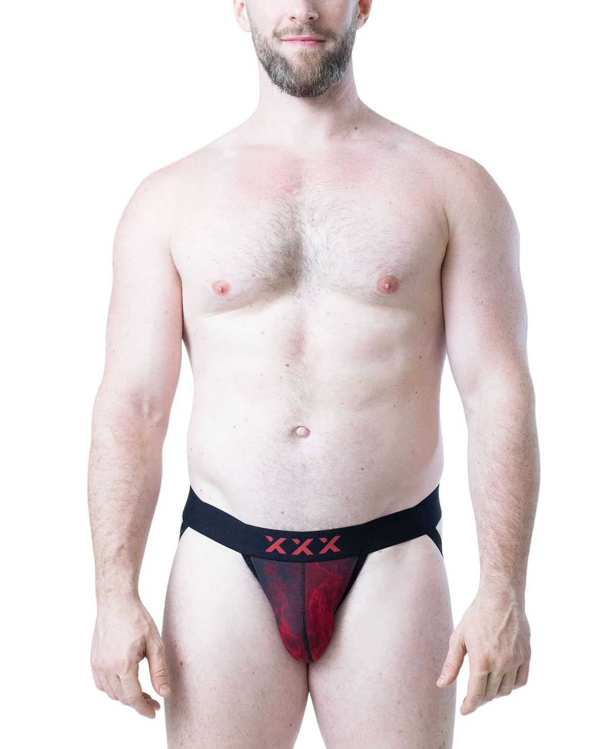 Male model wearing black and red flame-patterned jockstrap with XXX detail on waistband by Nasty Pig