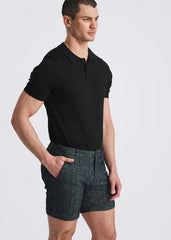 Man wearing POSTMARC black short-sleeve polo shirt and navy blue herringbone jacquard stretch knit chino shorts with side pockets