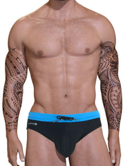 Muscular man with tribal arm tattoos wearing a black swim bikini with a blue waistband and front drawstring.