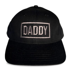 Black snapback cap with daddy embroidered in silver thread within a rectangular border by spunky monkee cap