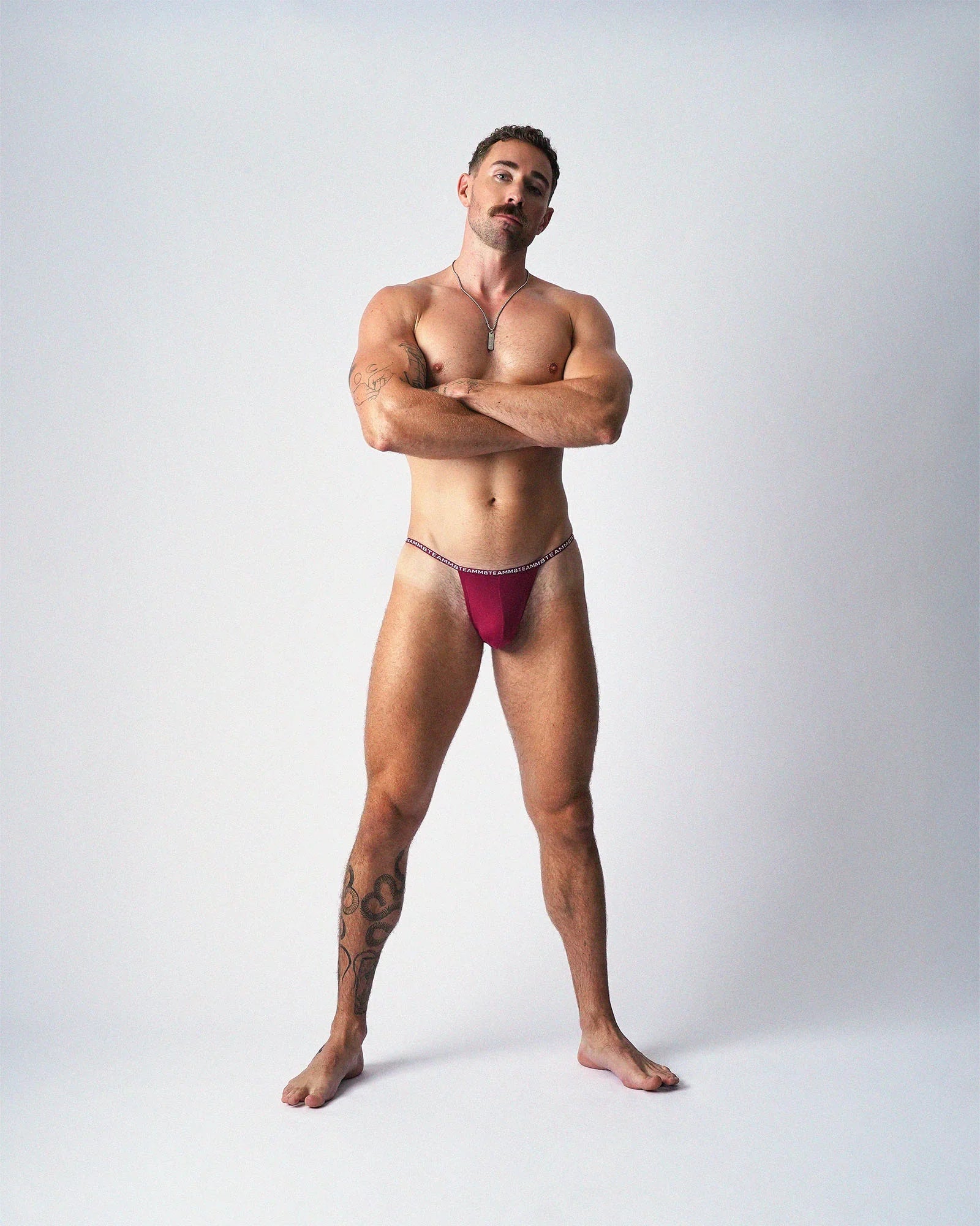 A muscular man models the teamm8 Glide Micro Brief in magenta against a white studio background.