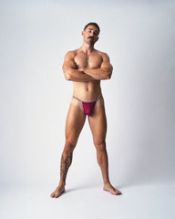 A muscular man models the teamm8 Glide Micro Brief in magenta against a white studio background.