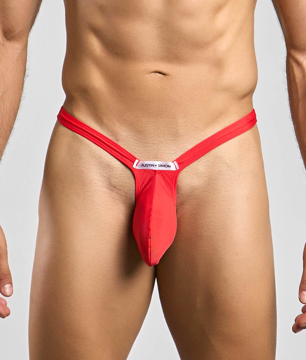 Red justin simon bulge thong with sleek form fitting design and white brand tag at the front