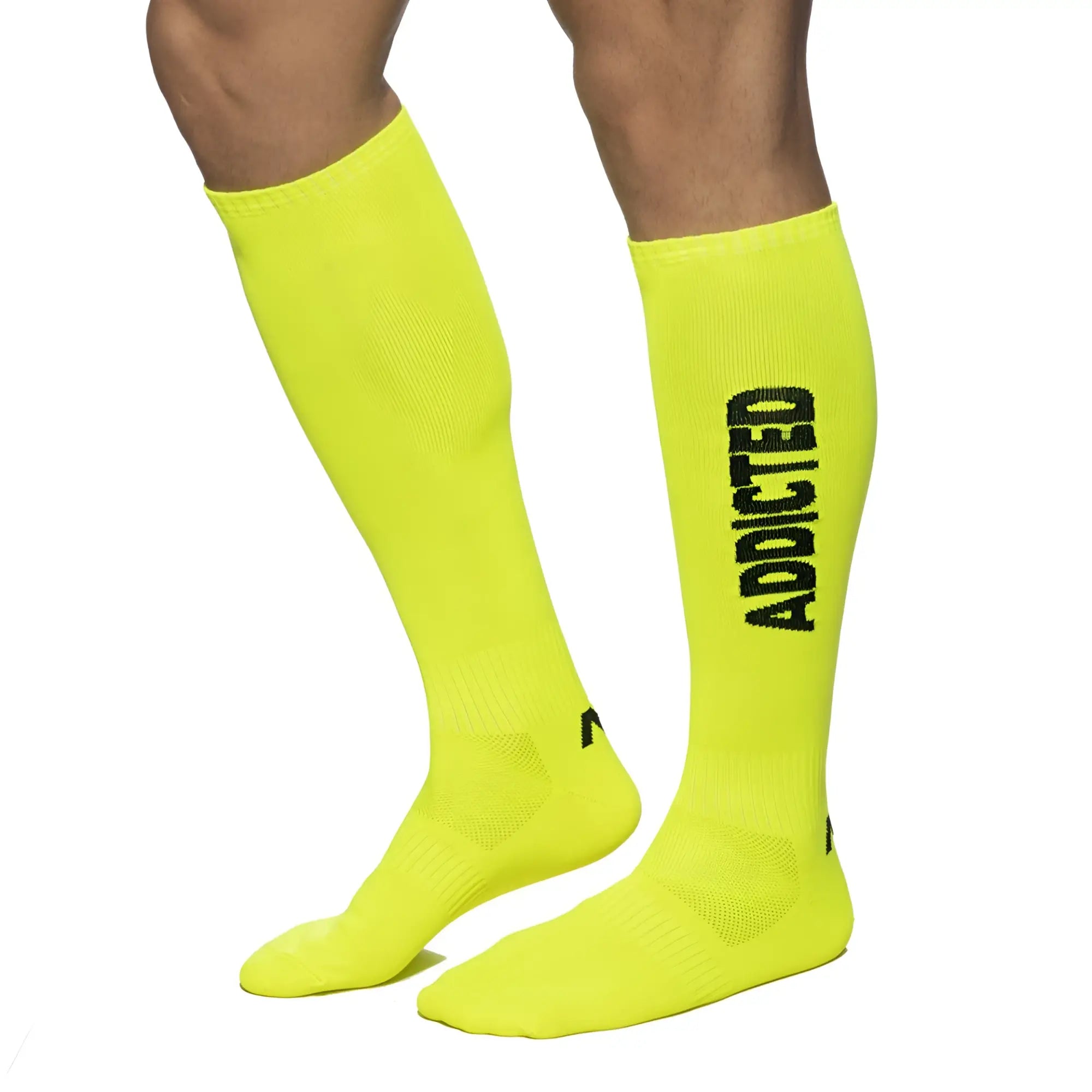 Bright neon yellow knee-high socks made of soft fabric with bold black addicted lettering on the side