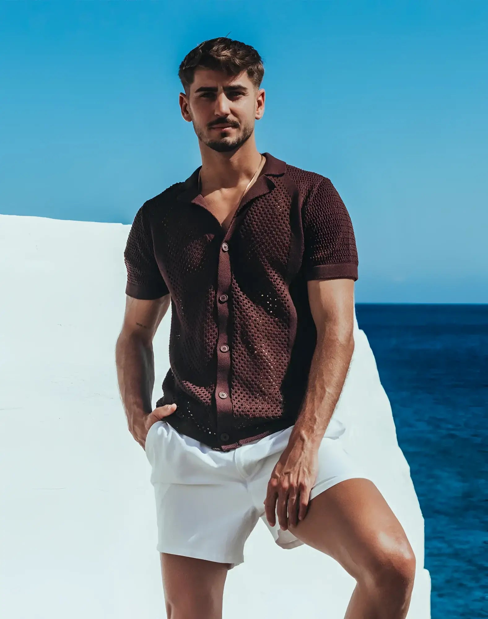 A man wearing an amafi knit shirt dark brown short-sleeved button-up with open collar and textured fabric