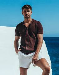 A man wearing an amafi knit shirt dark brown short-sleeved button-up with open collar and textured fabric