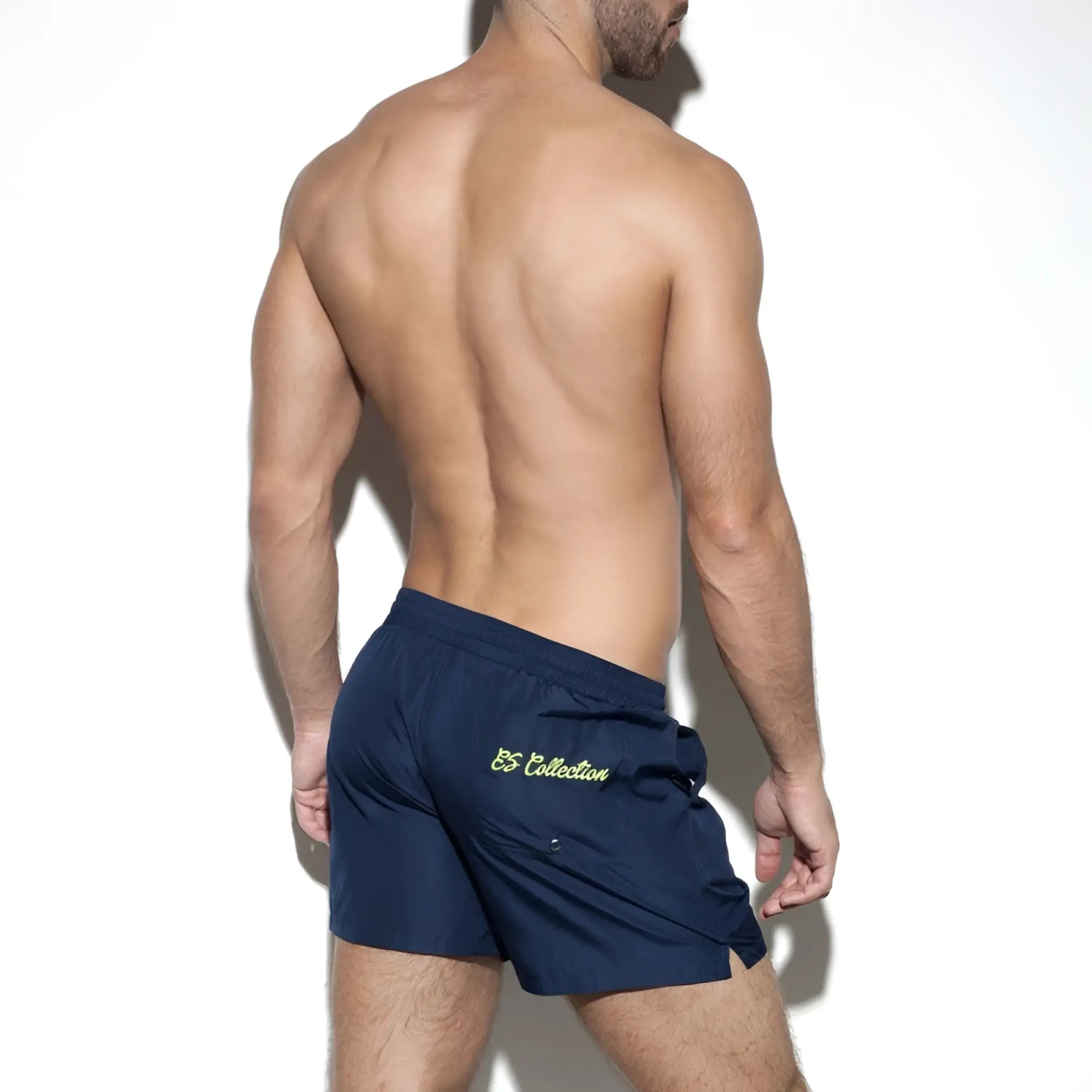 Navy blue basic boardshort with subtle yellow embroidered logo on the back pocket shown from the back side