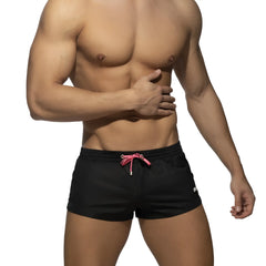 Black swim trunks basic mini short with pink drawstring and subtle white logo on the side for casual beachwear
