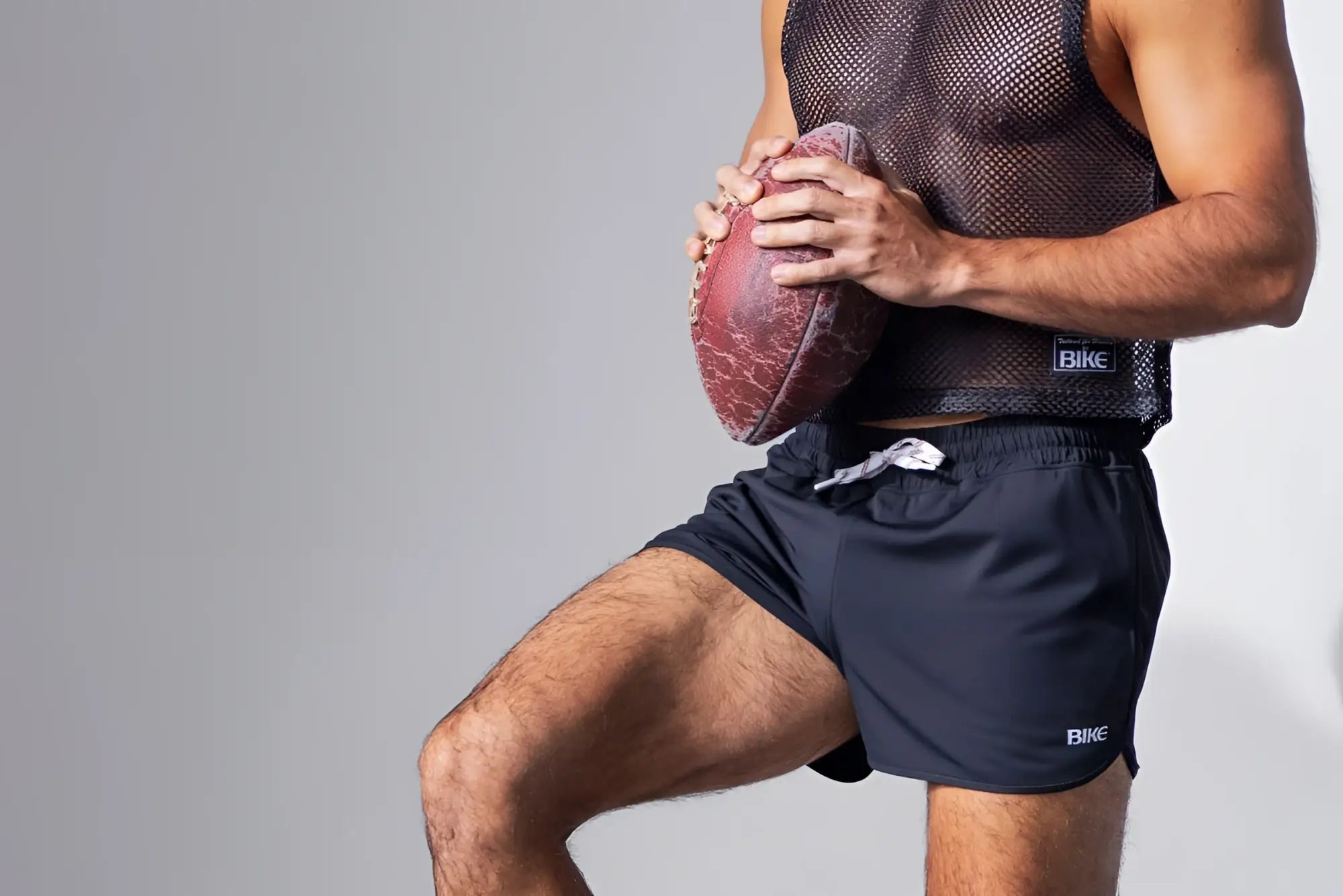 A worn reddish brown american football with scuff marks paired with a black bike athletic bam135 sleeveless mesh practice