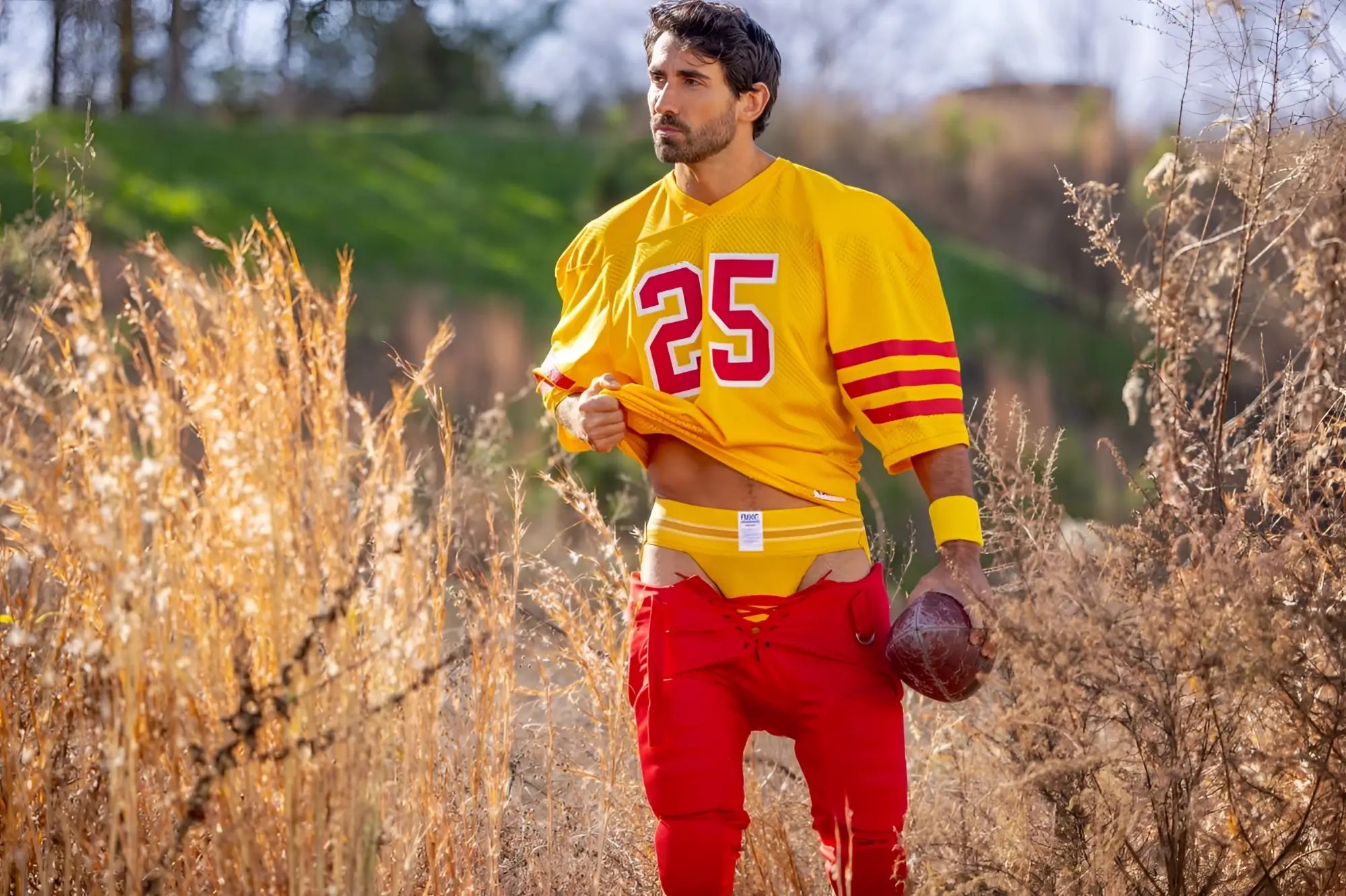 A man wearing a vibrant yellow football jersey with red numerals and stripes paired with red pants showing bike jockstrap