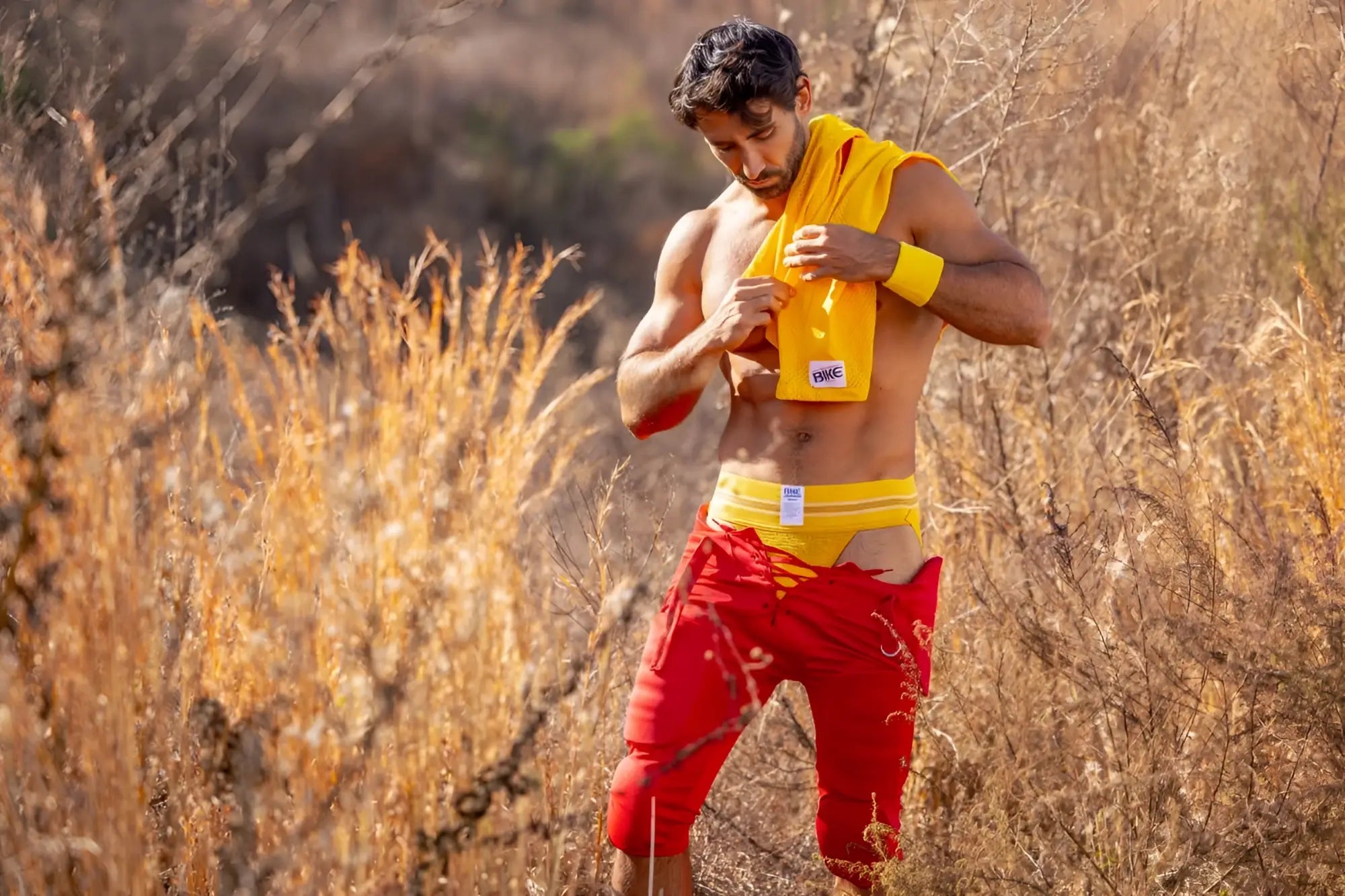Man wearing a yellow BIKE athletic jockstrap with a small white logo in an outdoor setting
