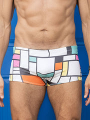 White swim trunks with bold geometric blocks of pink orange yellow teal and black in little boy blue design billy square cut suit mondrian inspired