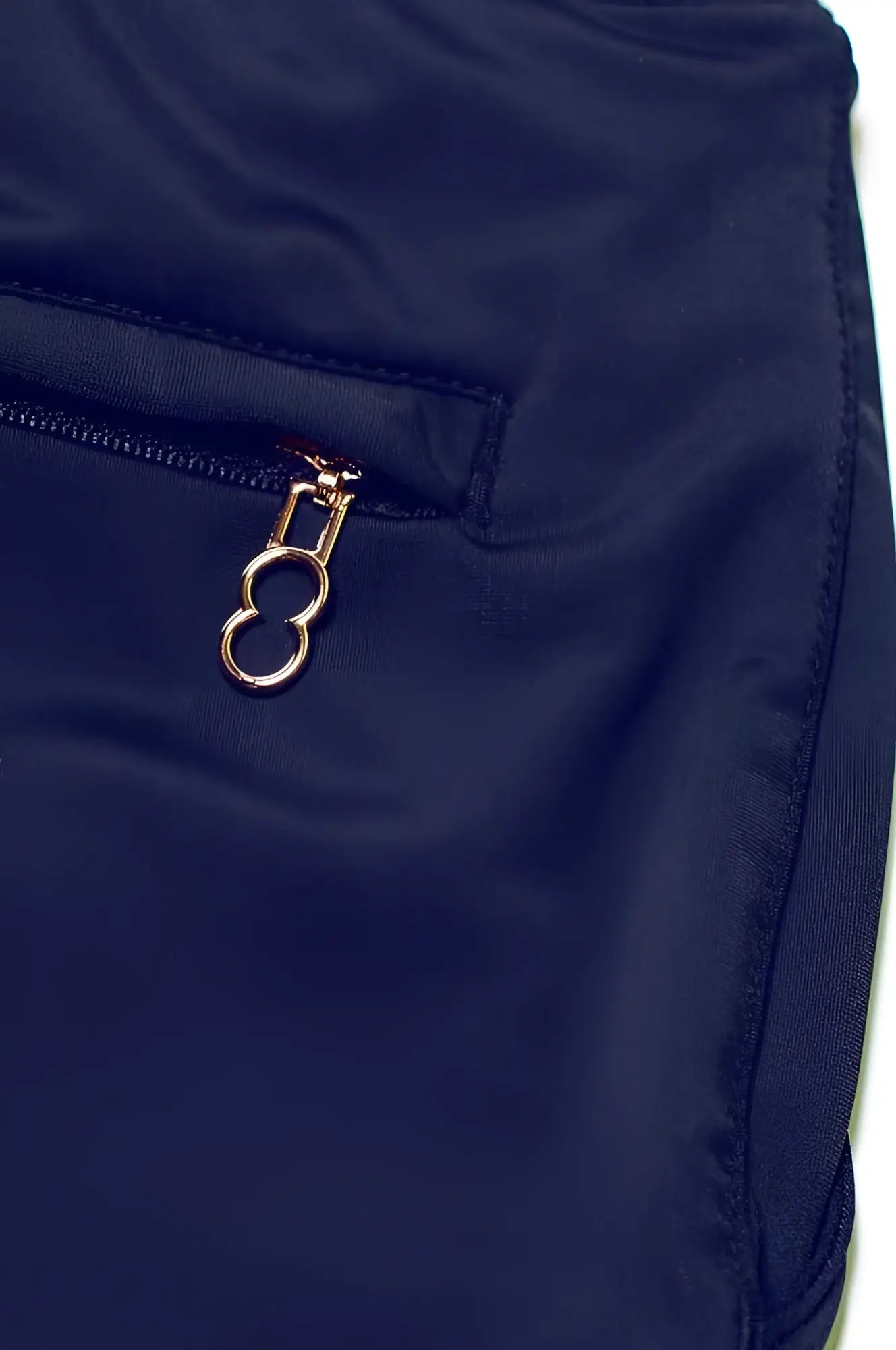 Navy blue bondi short made of nylon featuring a gold-toned zipper pull with an oval ring design