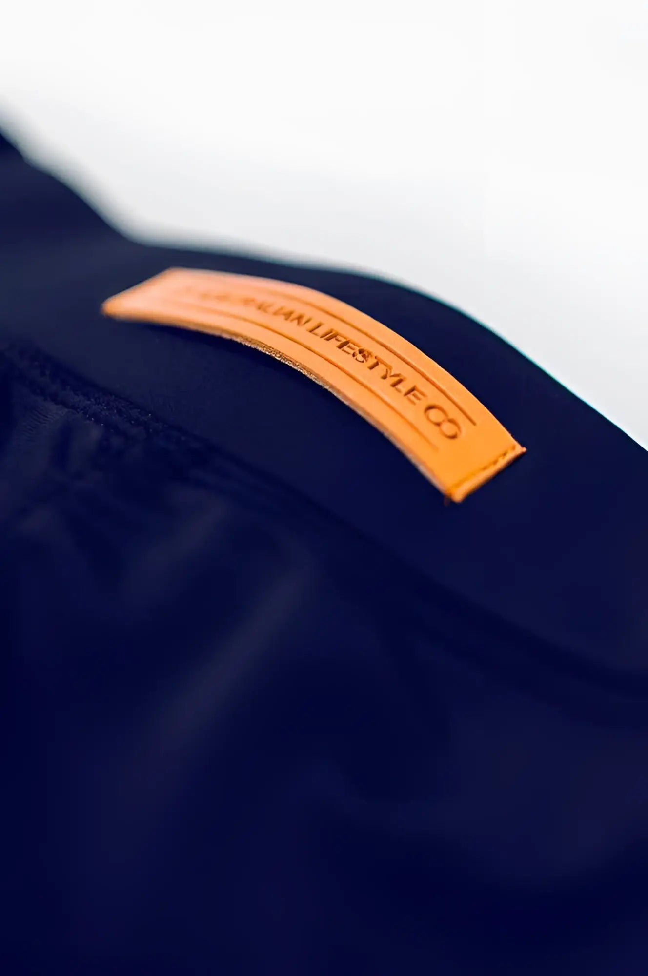 A tan leather lifestyle co patch sewn onto dark navy fabric of bondi short back side