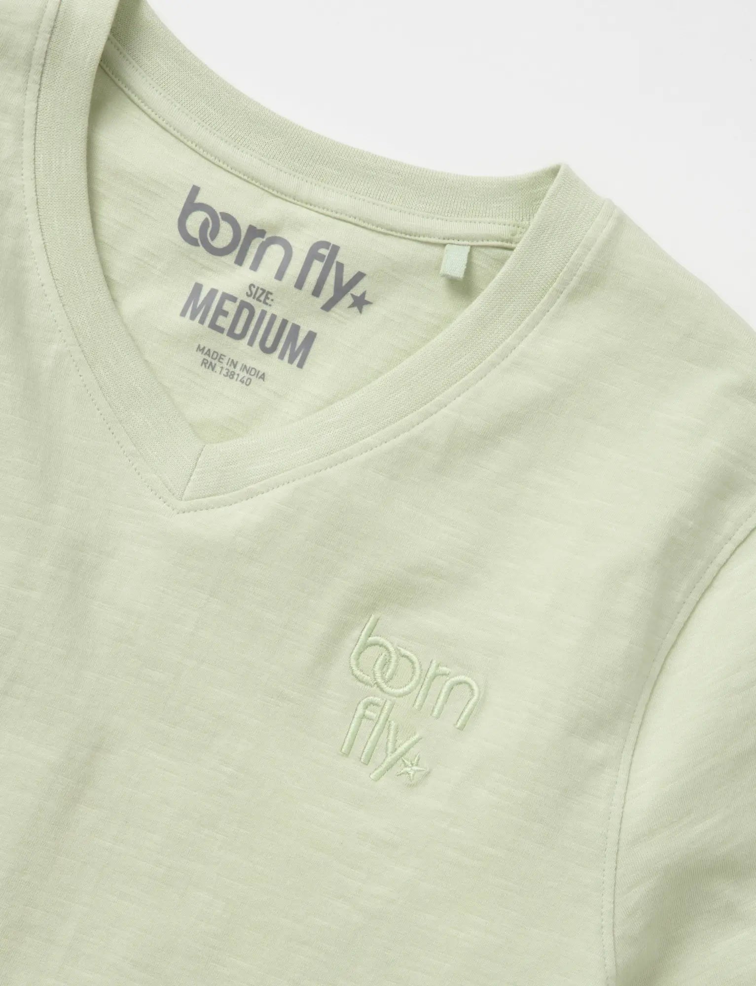 A light green cotton v neck born fly tee with subtle embroidered logo on the chest and matching collar tag