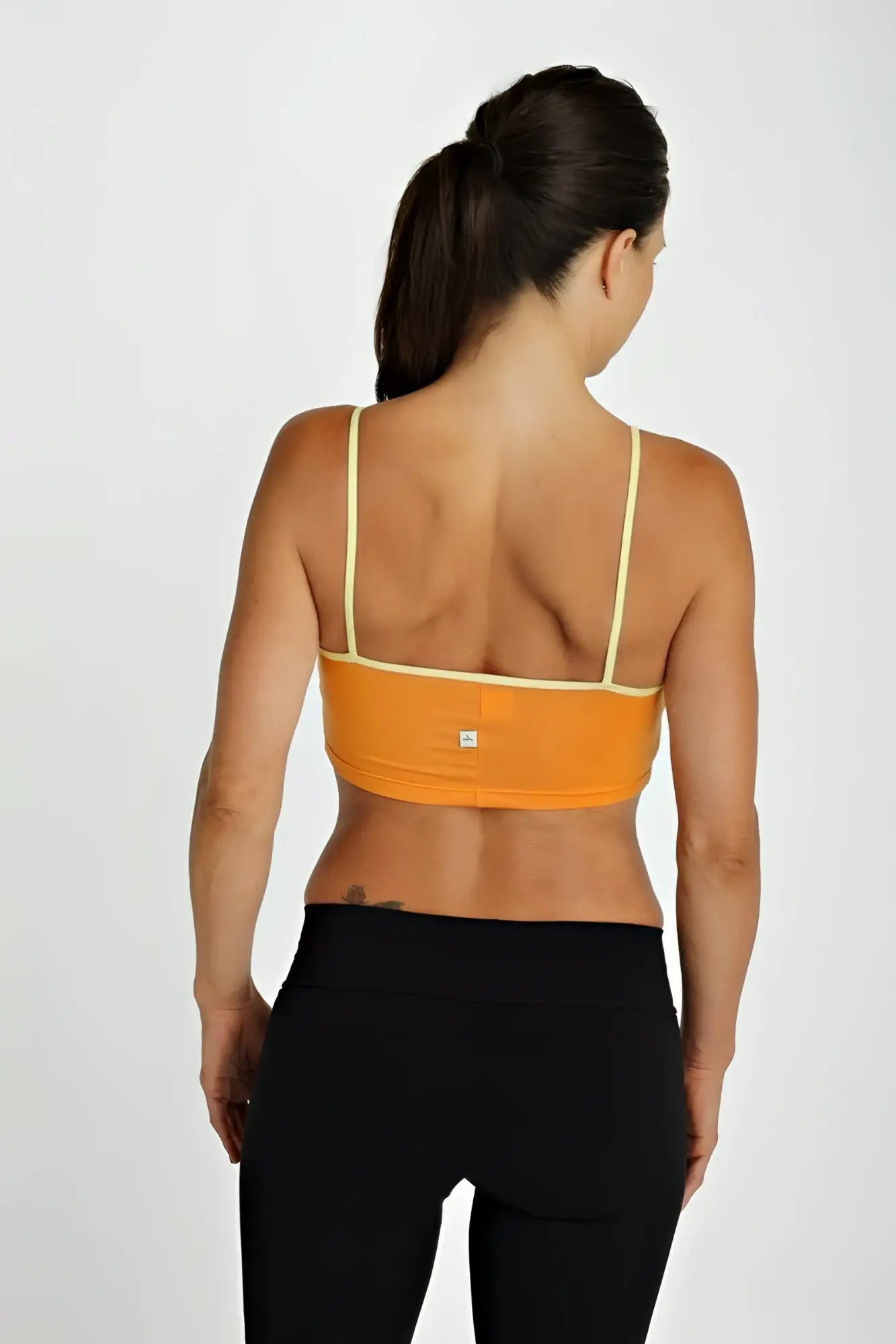 Bra top tangerine showing the back side in orange with thin matching yellow straps and a small brand logo