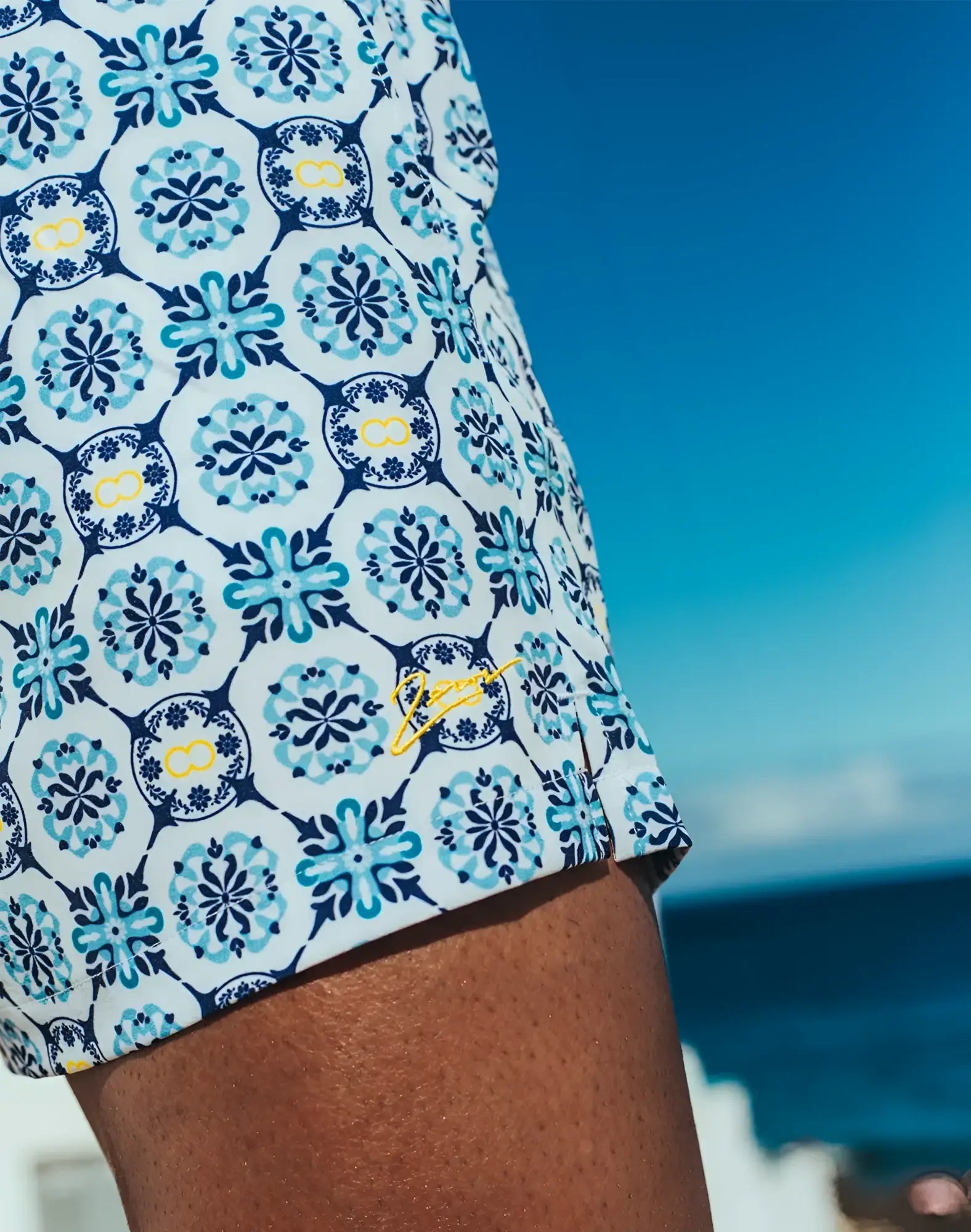 Byron swim short mykonos print white swim trunks with teal navy floral tile pattern yellow accents and embroidered logo