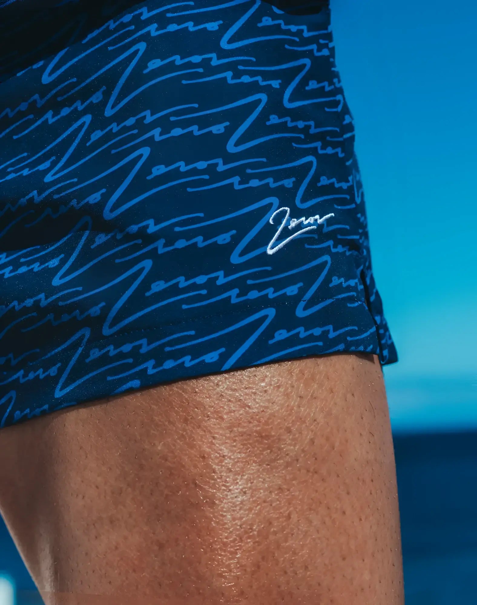 Dark blue Byron swim shorts with light blue wave pattern and small white signature logo on the side
