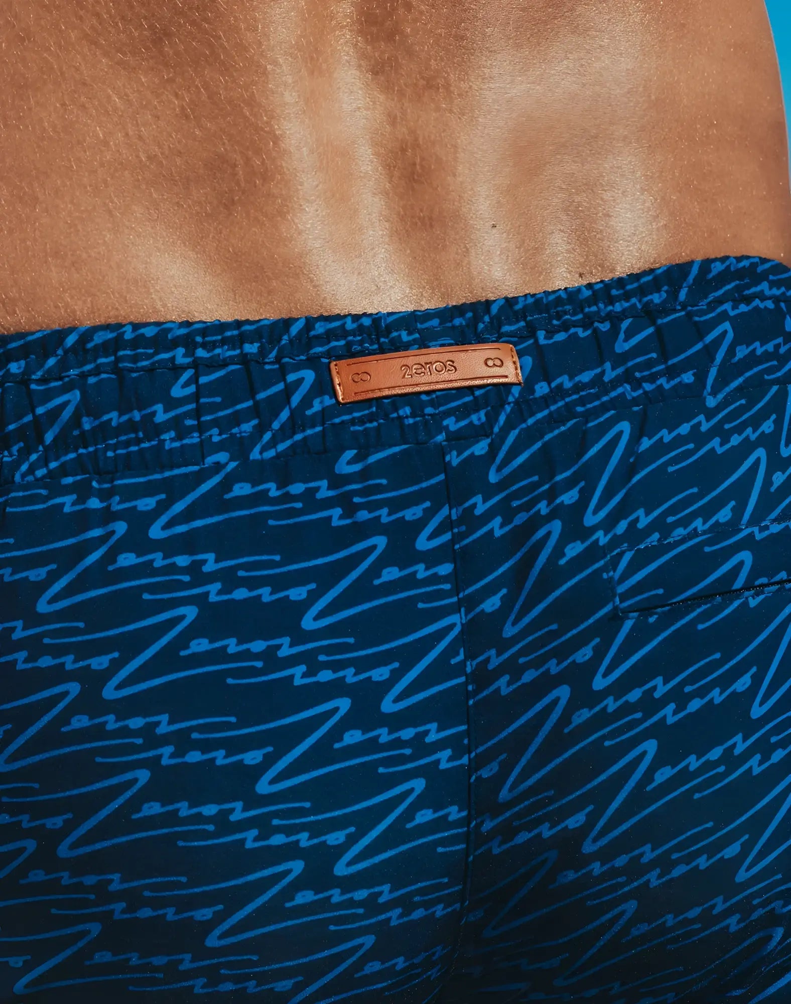 Dark blue byron swim short with light blue abstract line pattern and tan leather brand tag front view