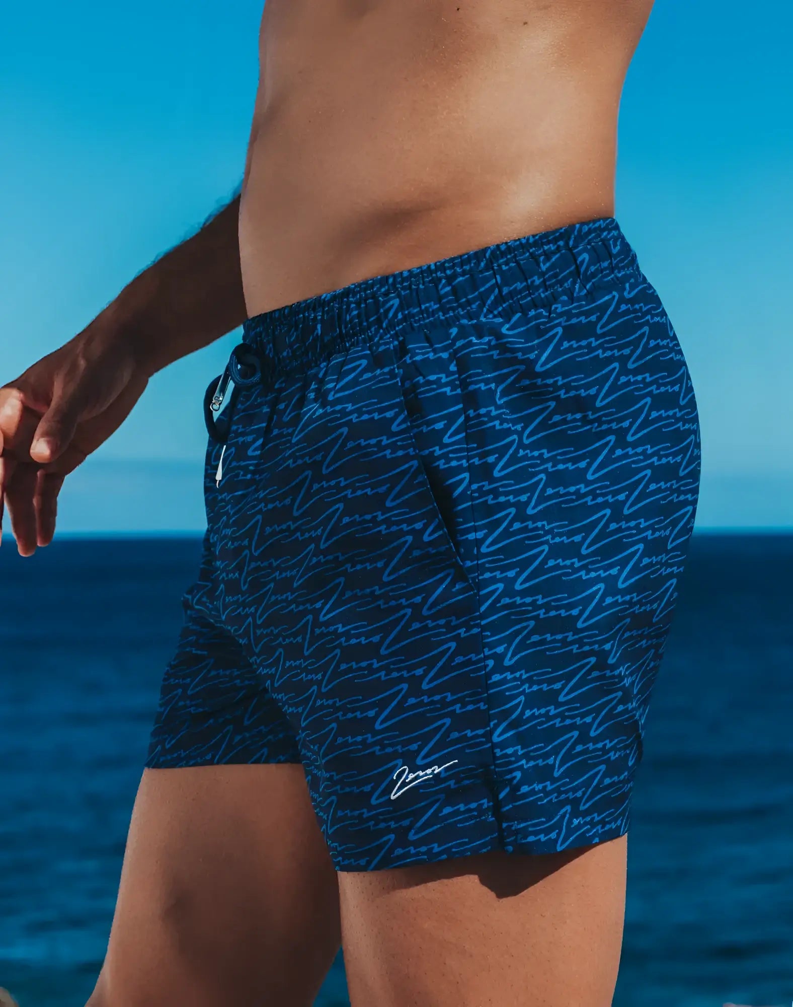 Dark blue byron swim shorts with light blue abstract wave pattern and white signature logo on lower right leg