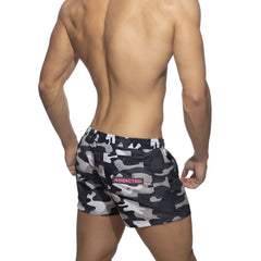 Back side of black and gray camouflage swim shorts with a pink addicted logo patch on the back pocket