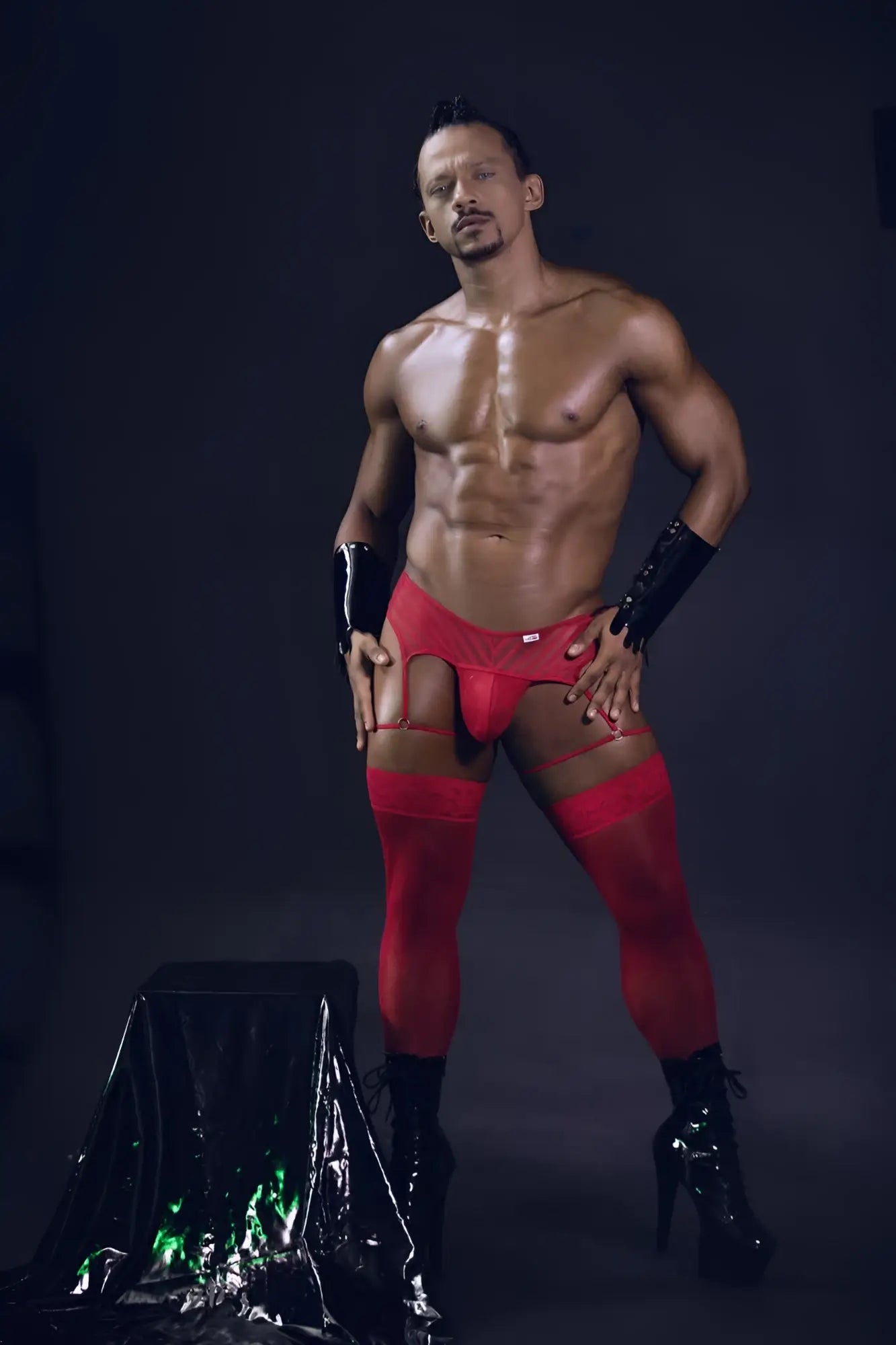 Red lace-trimmed high-waisted men’s briefs with mesh garter thongs matching thigh-high stockings and black patent gloves